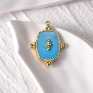 Detailed close-up of a 14k gold-plated blue enamel evil eye square pendant on ceramic