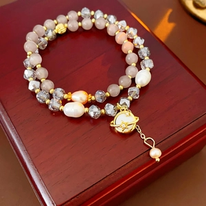Détail du bracelet double couche avec opales, perles baroques et pendentif planète doré