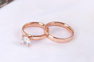Close-up of rose gold couple rings featuring a four-prong solitaire and polished band