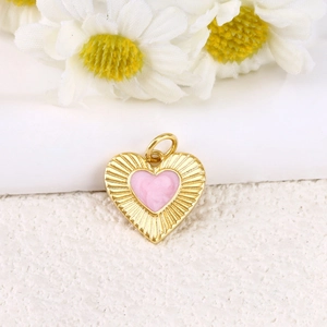 Macro detail of a gold-plated heart pendant with pink enamel and radial texture