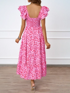 Détail d'une robe longue fleurie montrant la jupe à volants et le dos smocké