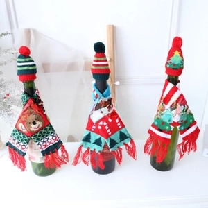Close-up of knitted mini Christmas hats and scarves set for wine bottle holiday decoration