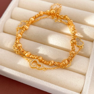 Macro detail of 24k gold-plated layered bracelet with zircon gourd pendants and beads