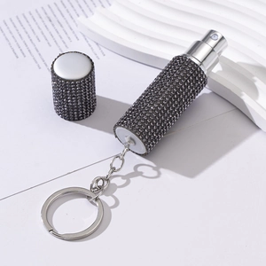 Detail of portable perfume spray bottle with black rhinestones and silver keychain