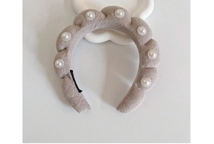 Detail of beige sponge twist headband with pearl embellishments and wave design