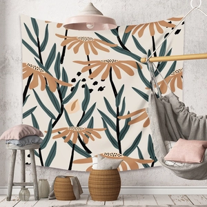 Detail of bohemian tapestry featuring large orange flowers and green leaves on a white wall