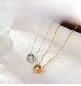Détail de pendentifs cœur en or et argent avec zircone sur tissu blanc
