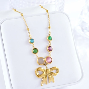 Bohemian gold bow necklace with multi-colored cat eye stones on a white jewelry box