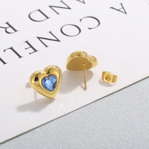 Detail view of gold heart stud earrings with blue crystal inlay on a white card