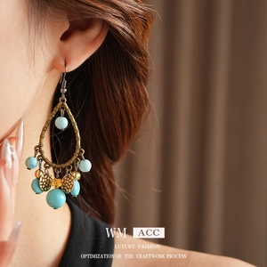 Ethnic drop earrings featuring turquoise beads and bronze metal on a model