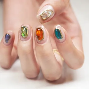 Detailed close-up of nail stickers with colorful gemstones and metallic gold frames