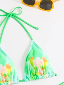 Detailed top view of a green floral bikini top with yellow sunglasses on white background