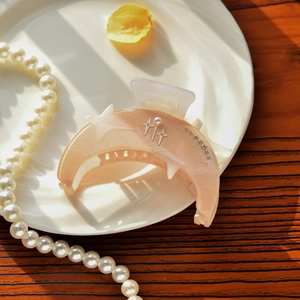 Detail of peach pink crescent moon hair claw with gold glitter, stars and pearls