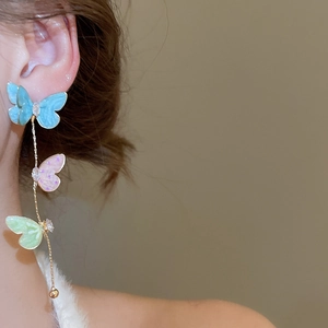 Detail of long triple butterfly tassel earrings with colorful enamel on a model