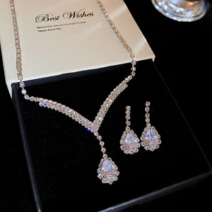 Macro shot of silver teardrop necklace and earrings set in a black velvet gift box