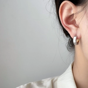 Detail shot of a minimalist two-tone curved huggie earring in polished gold finish