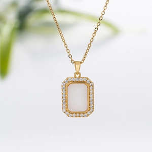 Macro detail of gold geometric square pendant with white shell inlay and zircon border