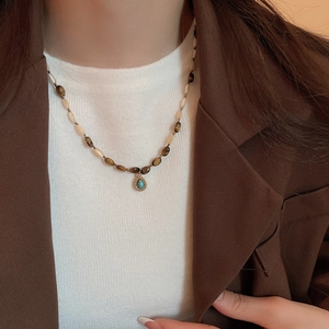 Close-up of beaded tiger eye necklace with turquoise pendant on a female model