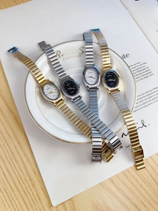 Macro shot of oval quartz watches with gold and silver metal chain straps on a plate