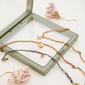 Détail d'un ensemble de bracelets plaqués or 18k avec breloques cœur et abeille sur cordon