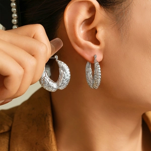 Vintage hollow wing feather earrings in silver finish on a professional model