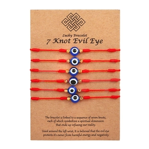 Adjustable 7-knot red string friendship bracelets with blue evil eye beads on a display card