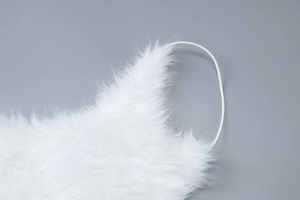 Close-up of white plush faux fur texture with delicate straps on a cocktail dress