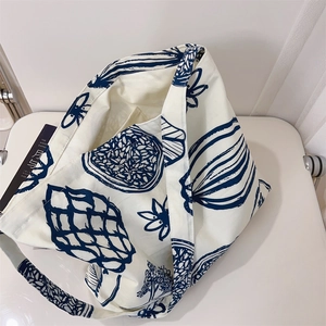 Détail d'un sac cabas en toile avec des motifs botaniques bleu marine sur tissu crème