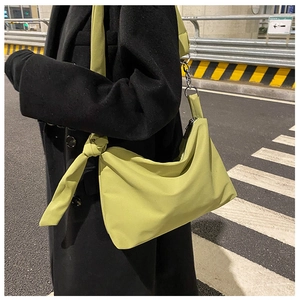 Model wearing avocado green nylon crossbody bag over a long black wool coat