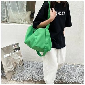 Detailed shot of large vibrant green nylon tote bag worn over the shoulder by a model