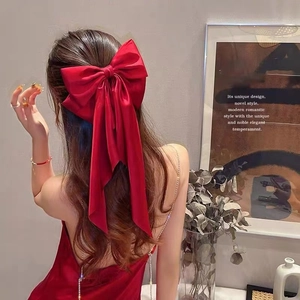 Elegant large red satin bow hair clip with long streamers on female model hairstyle