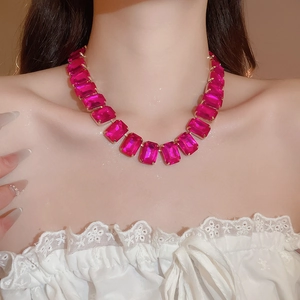 Close-up of model wearing luxury gold necklace with large rose red square rhinestones