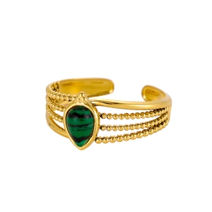 Detail of vintage gold-plated titanium ring with green stone and beaded texture