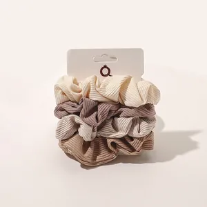 Set of four ribbed fabric scrunchies in cream, pink, and earth tones on display card