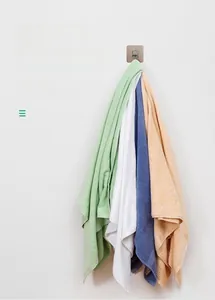 Detail of minimalist wooden wall hook holding five thick colorful cotton towels for storage