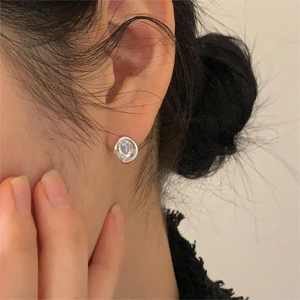 Close-up of minimalist silver earring with iridescent aurora stone on a model's ear