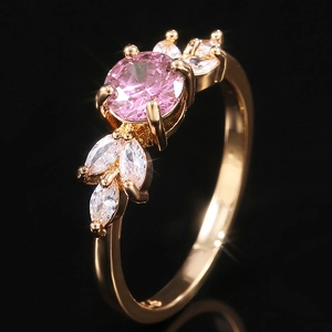 Macro view of a gold-plated ring with a large pink round zircon and leaf-shaped stones