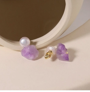 Nahaufnahme von lila Amethyst Rohkristall-Ohrsteckern mit einer kleinen weißen Perle