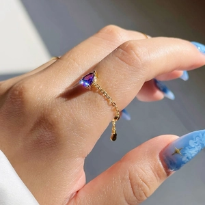 Détail d'une bague chaîne en or ajustable avec une pierre violette en forme de goutte
