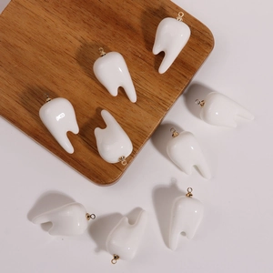 Macro detail of white tooth pendants with gold rings for DIY creative jewelry making