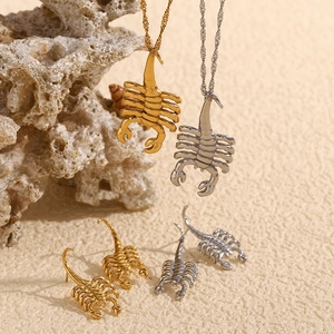 Detail view of gold and silver scorpion pendant necklaces and earrings on coral rock