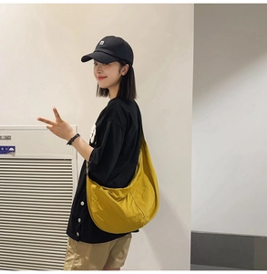 Vue détaillée d'un sac demi-lune en nylon jaune porté en bandoulière pour homme