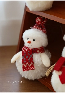 Close-up of plush snowman ornament with knitted hat and scarf on wooden steps