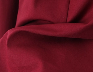 Macro de la texture du tissu rouge montrant le tissage et le drapé de la robe