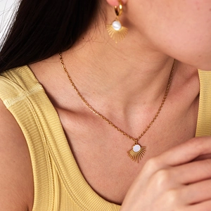 Detail of vintage gold sunburst necklace and earrings set with white stone on a model