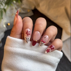 Long almond press-on nails featuring red French tips, leopard print, and 3D cherry accents