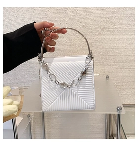 Detail of white leather handbag with diagonal stitching and round silver metal handle