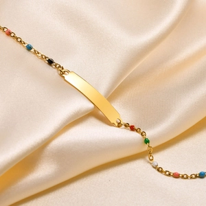 Macro shot of gold cross-link bracelet with colorful round beads on beige silk fabric