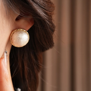 Close-up of gold-plated cotton pearl round earrings shown on a model for a vintage style