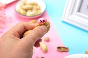 Dettaglio di un giocattolo antistress a forma di arachide con faccina e cordino pratico